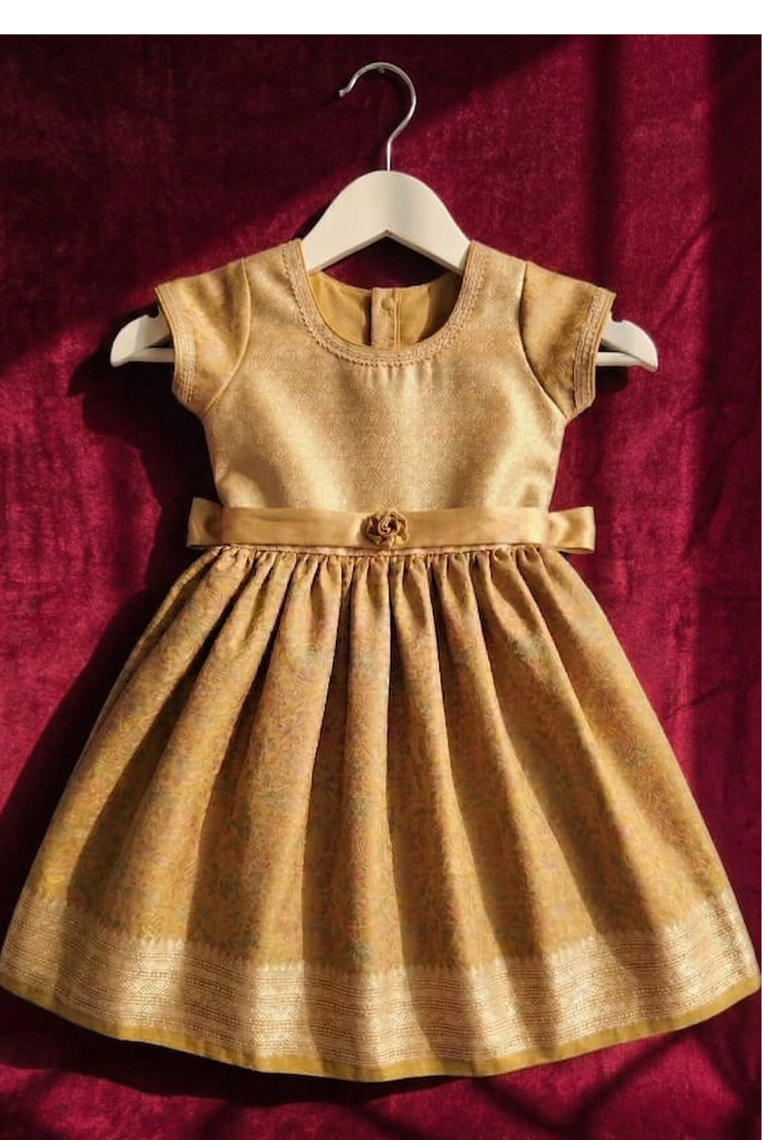 Gold dress on a hanger against a red fabric background